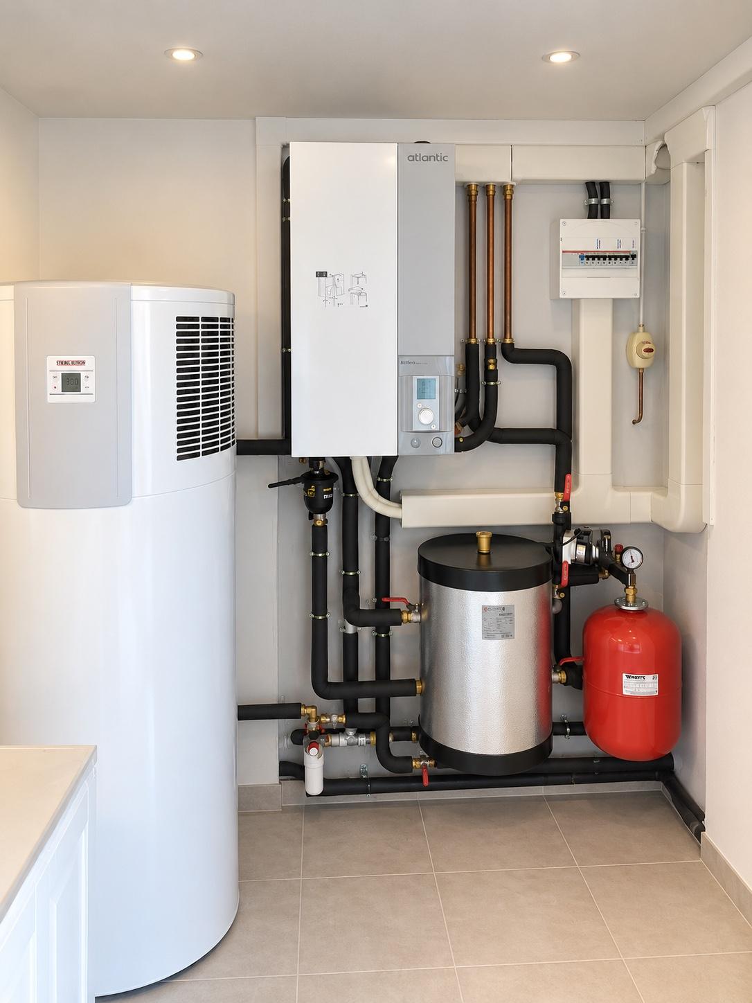 Module intérieur de pompe à chaleur air/eau installé par Priorité Environnement : unité murale, ballon d'eau chaude, bouteille de découplage, vase d'expansion et tableau électrique, tuyauterie calorifugée